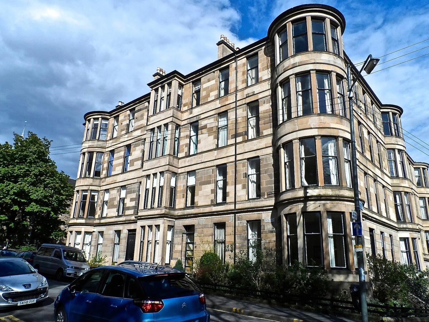 Curved blond sandstone tenement with stacked bay windows in Hillhead, Glasgow